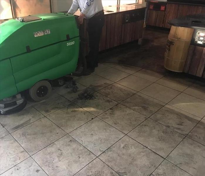 ride-on floor cleaner getting grime from fire off tile floor