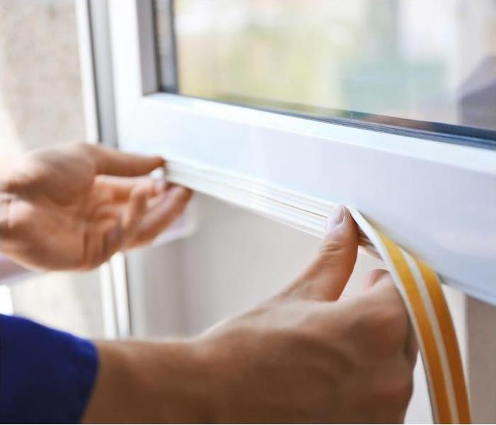 a person placing weather stripping on a white window
